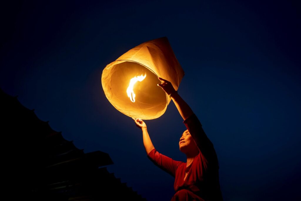 Woman letting fire go fire in paper lantern symbolizing letting go of what she can’t control when facts fail to convince others. 